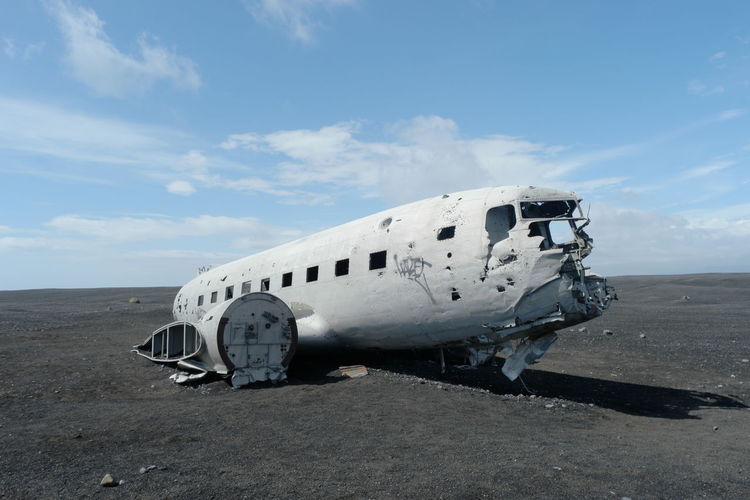 Abandoned airplane on landscape against sky