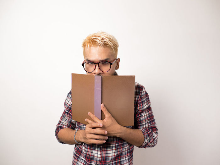Portrait of man holding book against white background