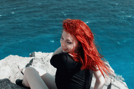 High angle view of young woman with redhead sitting against sea