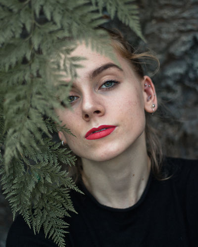Close-up portrait of young woman by plant