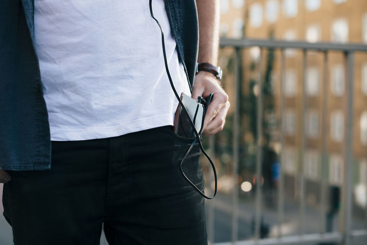 Midsection of man removing mobile phone from pocket in city