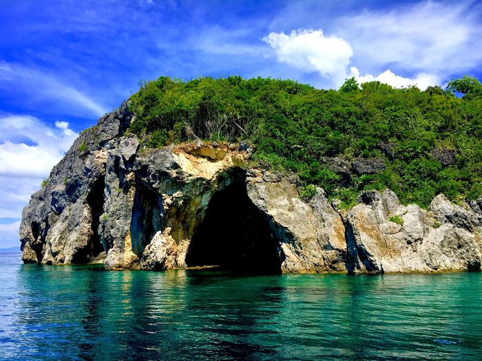Rock formation by sea against blue sky
