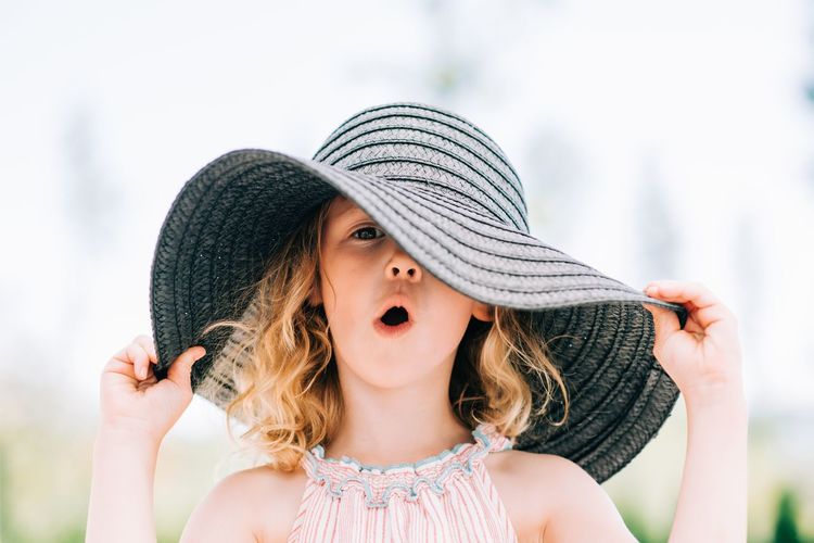 Portrait of a young girl pulling a funny expression with a sun hat on