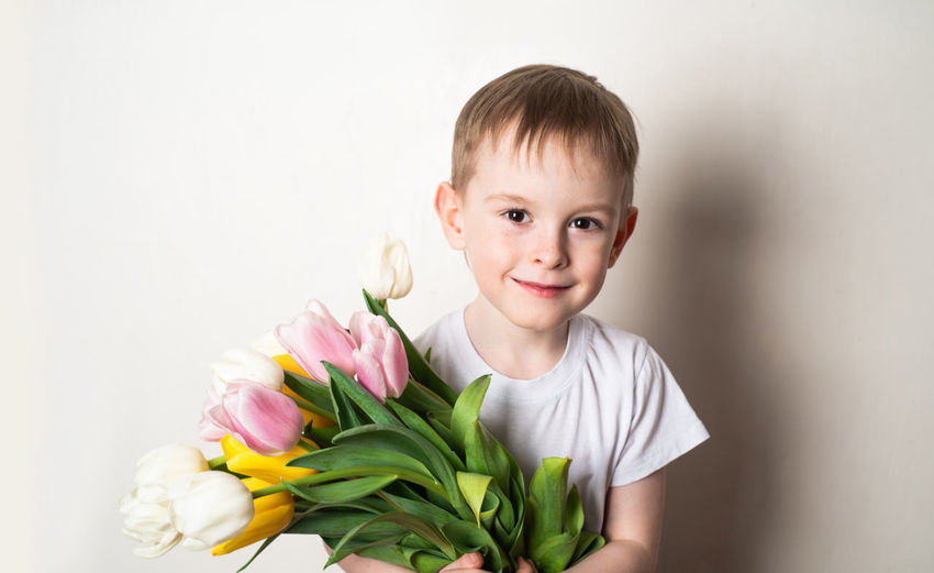 Portrait of cute girl holding bouquet against white background