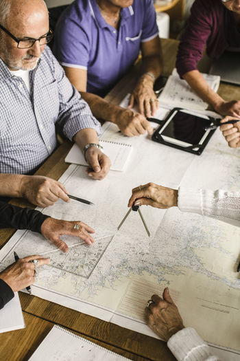 High angle view of elderly men and women with map at table during navigation course