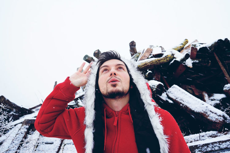 Man saluting while standing in snow against wood
