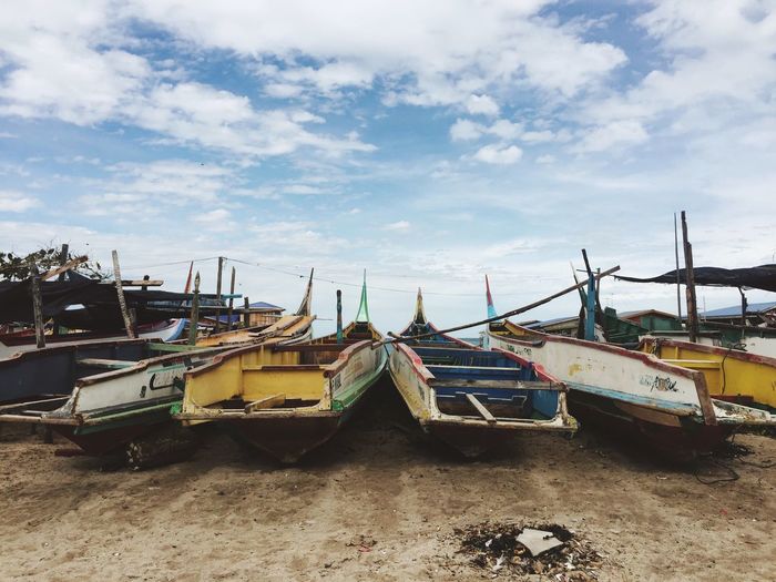 Boats moored at harbor against sky