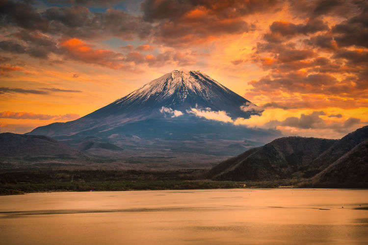 Scenic view of mount fuji mountain against cloudy sky during sunset