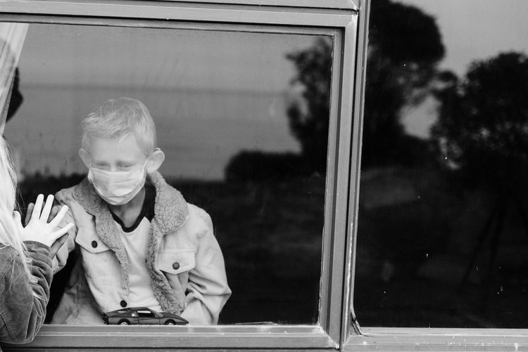 Portrait of boy sitting on window