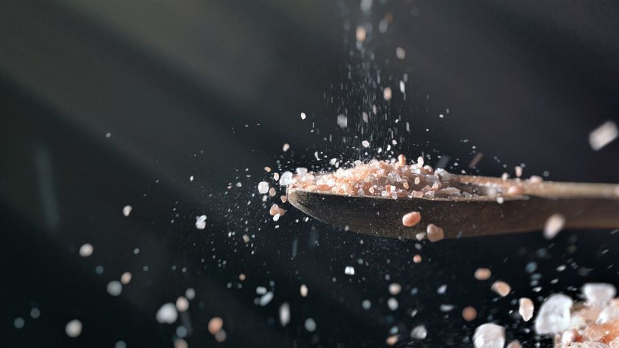 Close up of himalayan salt pouring from above on wooden spoon recipe seasoning ingredients