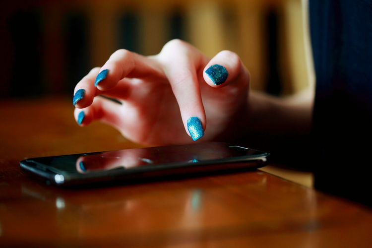 Cropped image of woman using phone at table