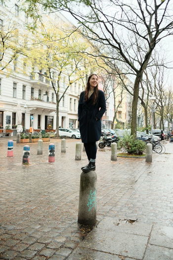 Portrait of young woman standing on footpath in city