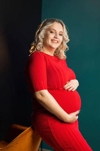 Portrait of beautiful pregnant woman standing at home