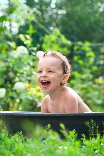 Boy laughing while sitting in baby bathtub