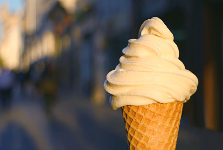 Vanilla soft serve ice cream cone with blurry walking street in background