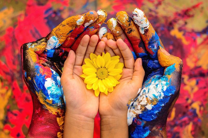Cropped image of painted hands holding flower