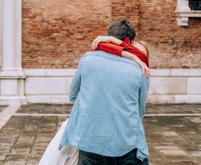Rear view of couple embracing against brick wall