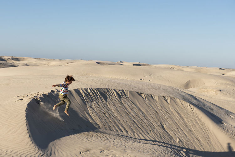 One kid jumping from a sand dune at dunas de la soledad