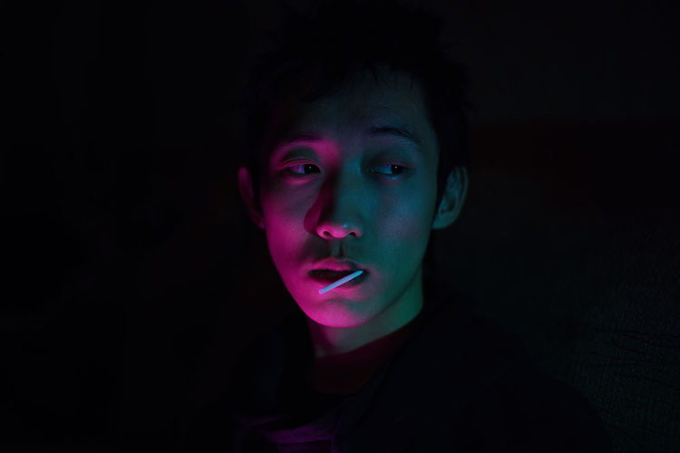 Portrait of young man against black background