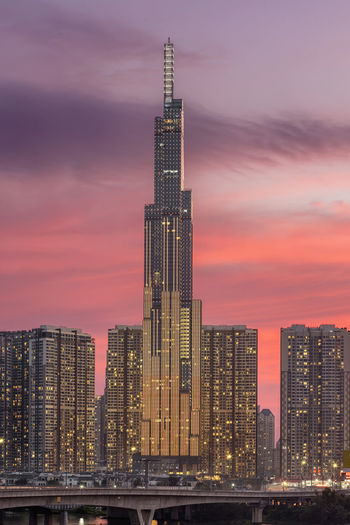 Illuminated modern buildings against sky during sunset