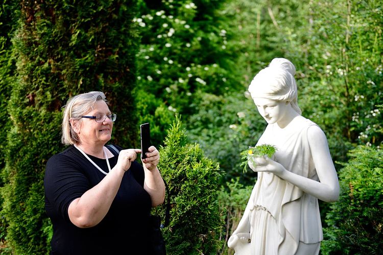 Senior woman photographing statue with smart phone at park