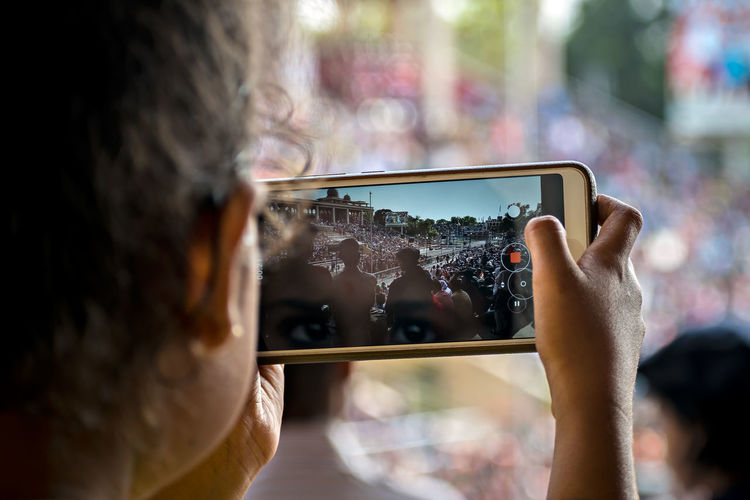 Young lady capturing video of beating retreat ceremony on her cell phone.
