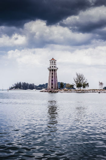 Lighthouse at beach against sky