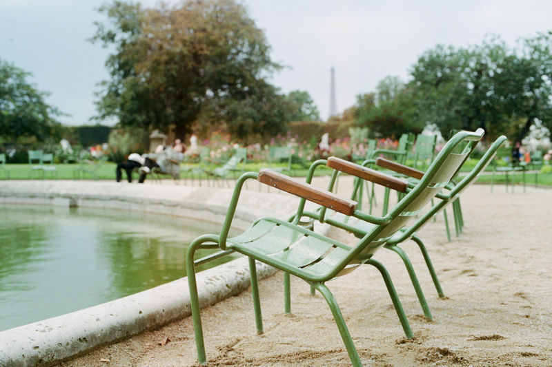 Empty chairs in park against sky