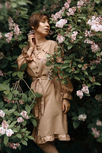 Beautiful woman standing by flowering plants