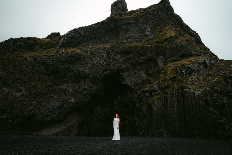 Woman standing on beach against rock formation