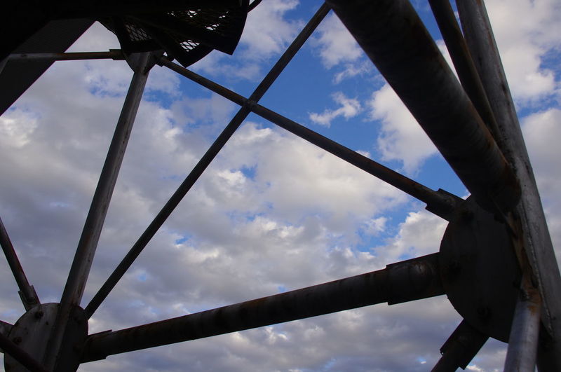 Low angle view of metal structure against cloudy sky