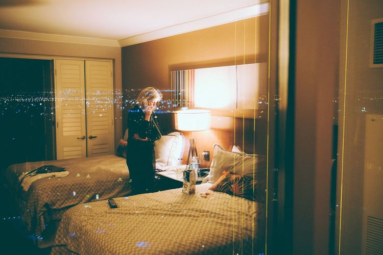 Reflection of woman talking on landline phone in hotel room