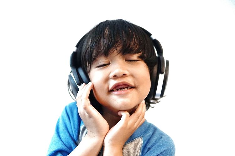 Cute boy listening music against white background