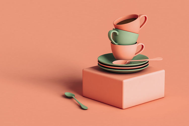Three dimensional render of three coffee cups stacked on top of plates lying on square block