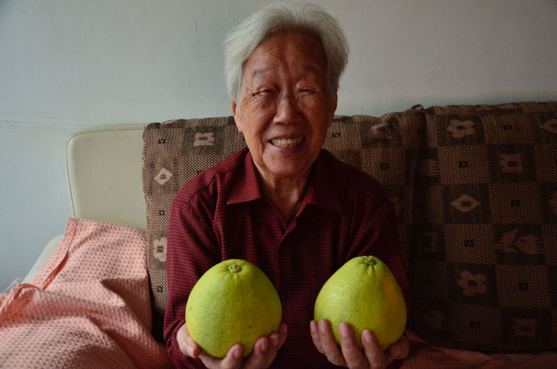 Front view of senior woman holding pomelos