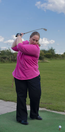Full length of woman playing golf on field