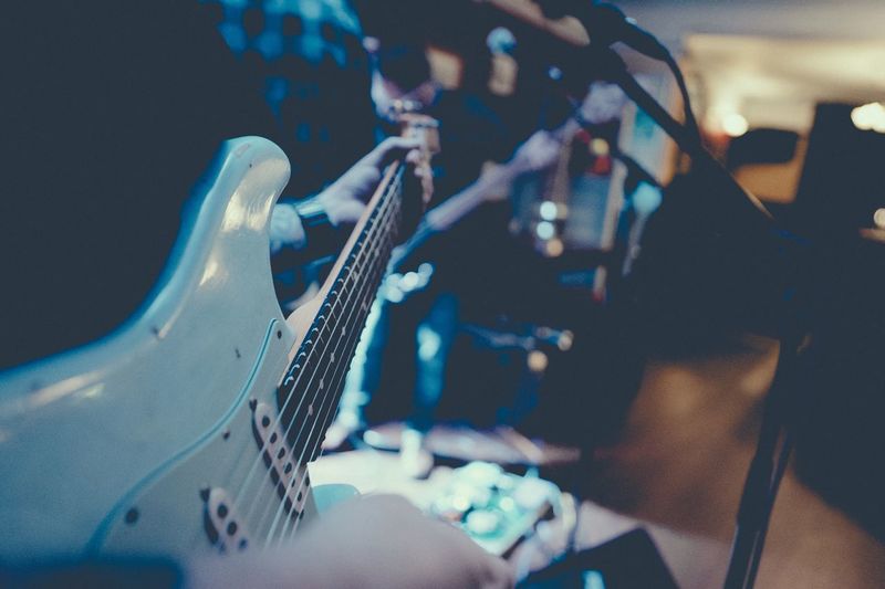 Midsection of musician playing guitar at nightclub