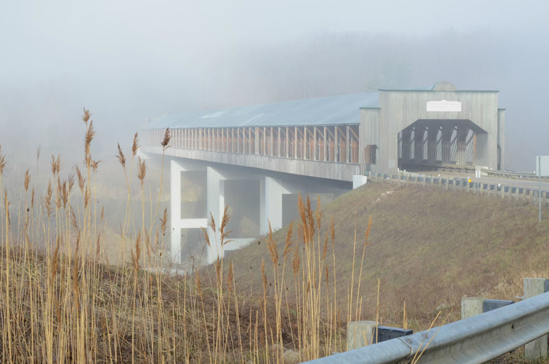 Concrete covered bridge on small highway on foggy morning