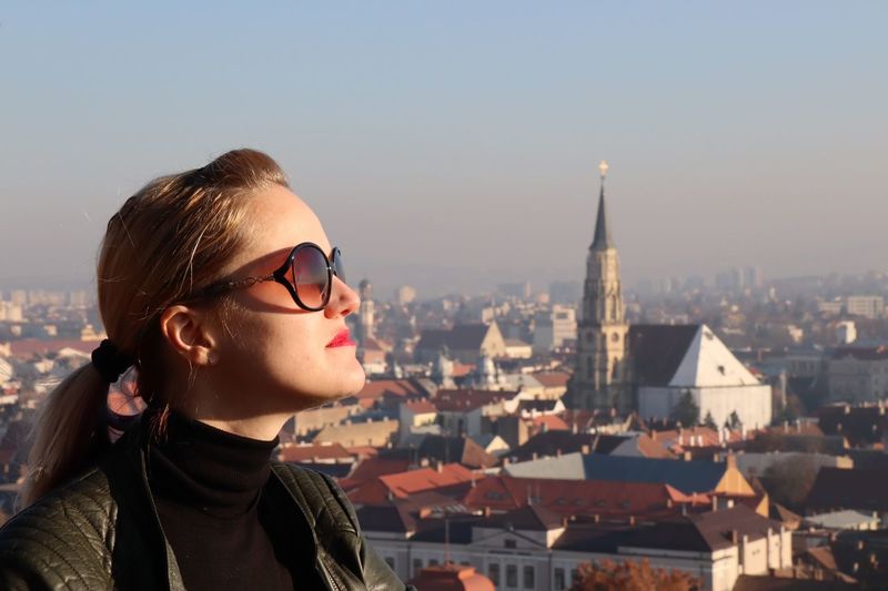 Woman wearing sunglasses against buildings in city