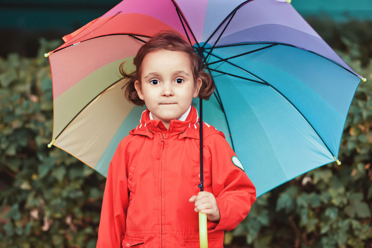 Portrait of cute girl standing in rain during rainy season