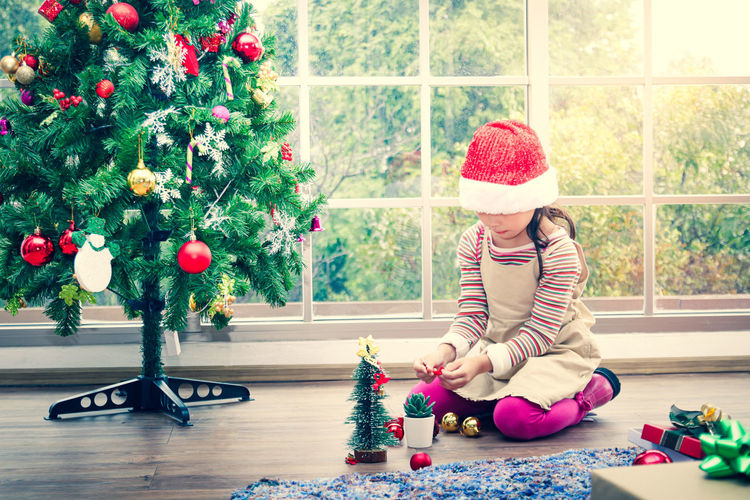 Full length of girl sitting on christmas tree