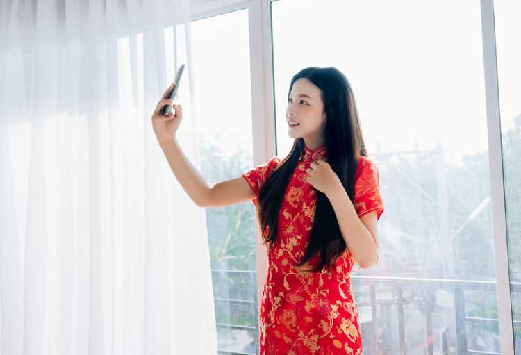 Young woman wearing traditional clothing while clicking selfie at home