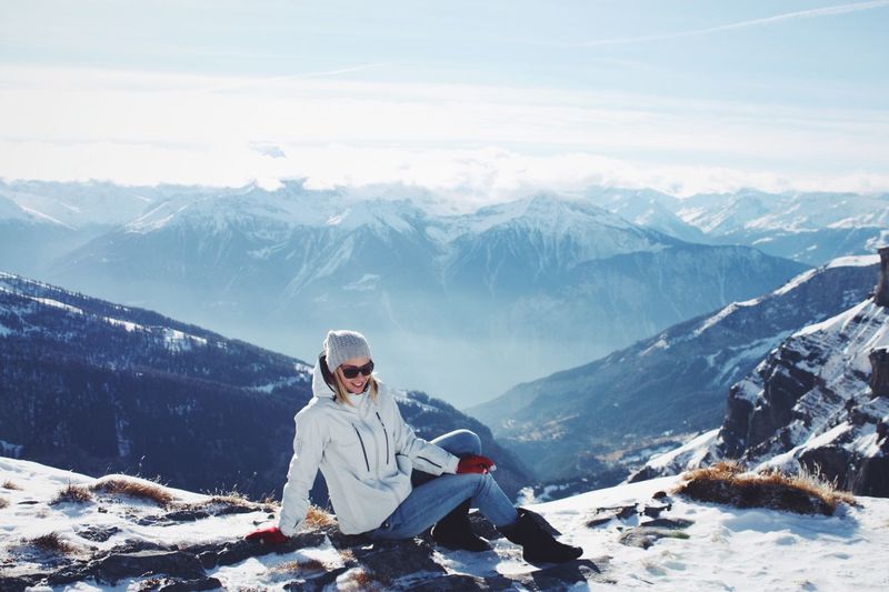 Full length of woman sitting on snowcapped mountain