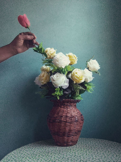 Cropped image of hand removing flower from vase