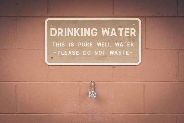 Text on placard with valve against concrete wall