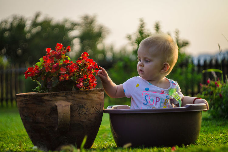 Little girl in a bowl next to flowers
