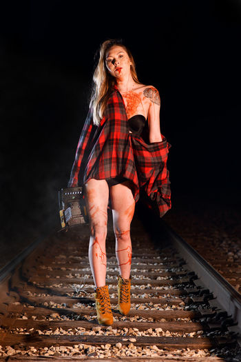 Portrait of young woman with chainsaw walking on railroad track
