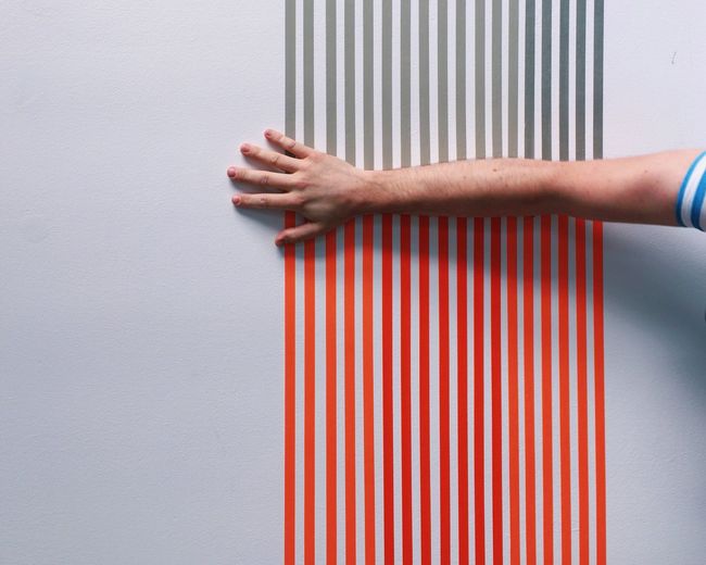 Cropped hand of man on wall with stripes
