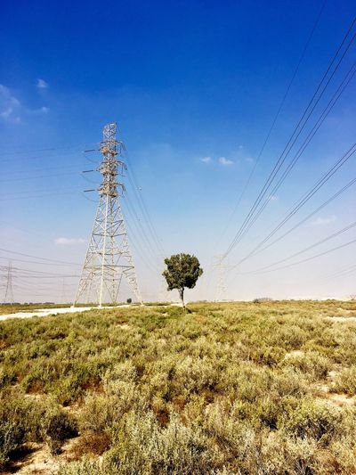 Electricity pylon on field against blue sky