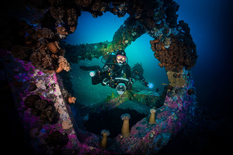 Scuba divers filming concrete cube underwater